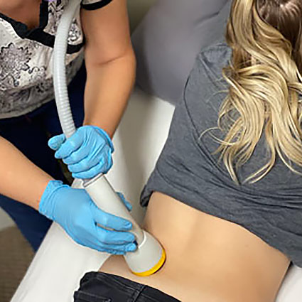 Person holding their lower back area indicating discomfort in a bright clinic